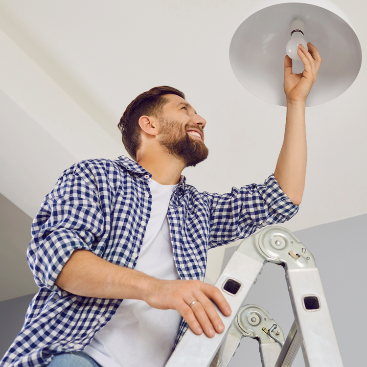 Man climbing a step ladder to change a light bulb